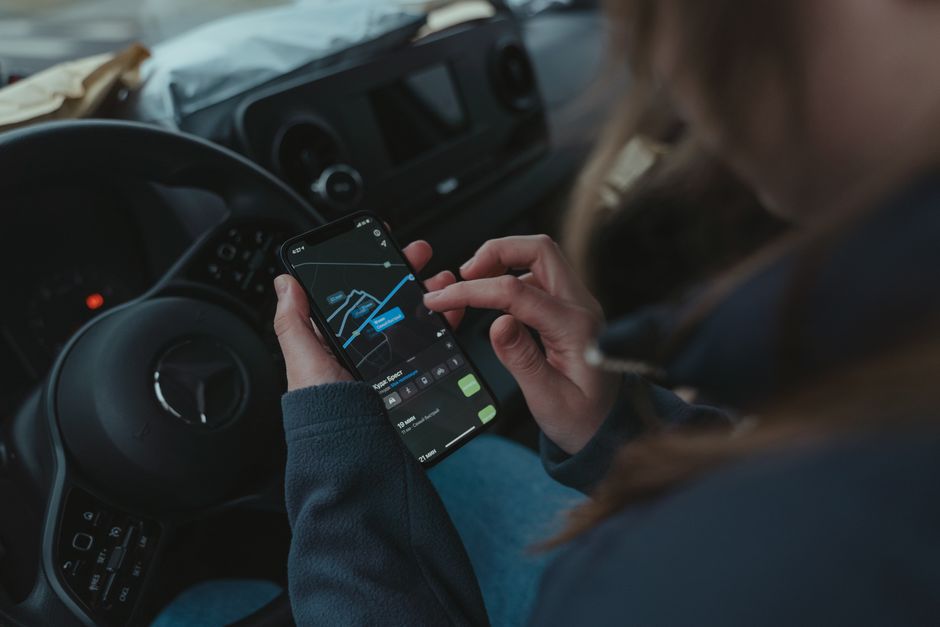 Notícias São Paulo. — Person using GPS navigation app on smartphone inside car for directions.